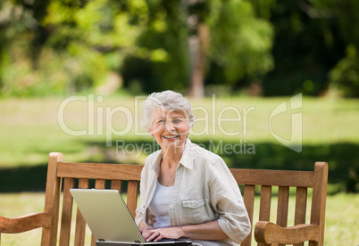 Mature woman working on her laptop on the bench