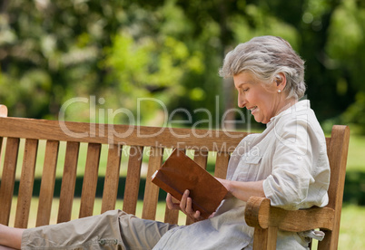 Reired woman reading a book on the  bench