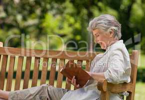 Reired woman reading a book on the  bench