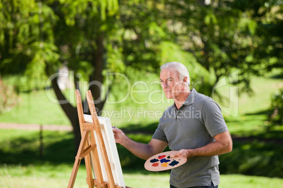 Senior man painting in the garden