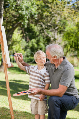 Happy Grandfather and his grandson painting in the garden