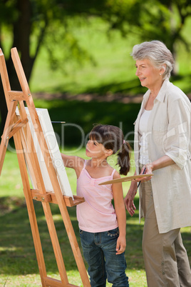 Grandmother and her granddaughter painting in the garden