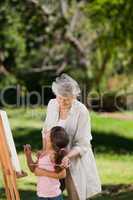 Grandmother and her granddaughter painting in the garden