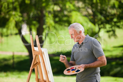 Senior man painting in the garden