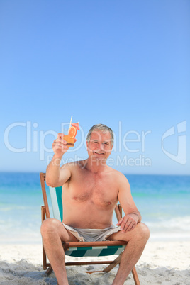 Senior man drinking a cocktail on the beach Senior man drinking a cocktail on the beach