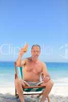 Senior man drinking a cocktail on the beach