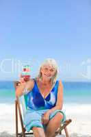 Elderly woman drinking a cocktail on the beach