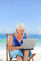 Woman working on her laptop on the beach