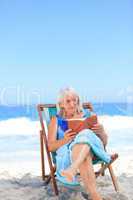 Senior woman reading a book on the beach