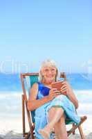 Senior woman reading a book on the beach