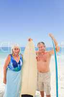 Mature couple with their surfboard