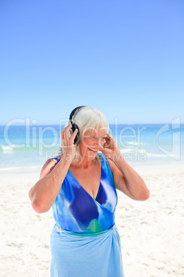 Senior woman listening to some music beside the sea