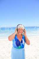 Senior woman listening to some music beside the sea