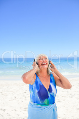 Senior woman listening to some music beside the sea