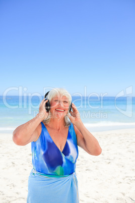 Senior woman listening to some music beside the sea