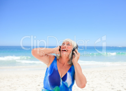 Senior woman listening to some music beside the sea