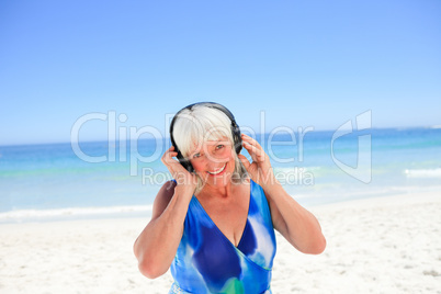 Senior woman listening to some music beside the sea