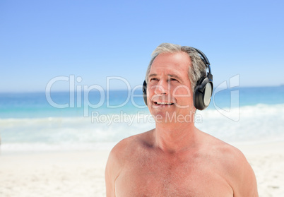 Retired man listening to some music on the beach