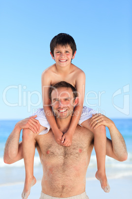 Father having son a piggyback on the beach