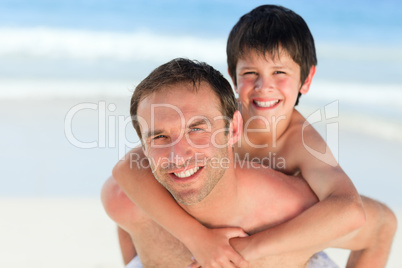 Father having son a piggyback on the beach