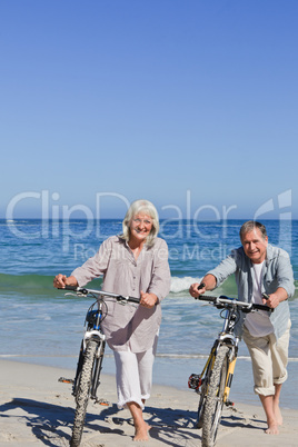 Mature couple with their bikes on the beach