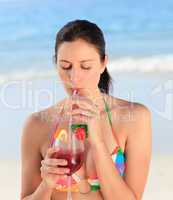 Beautiful woman drinking cocktail on the beach