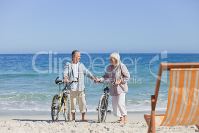 Elderly couple with their bikes on the beach