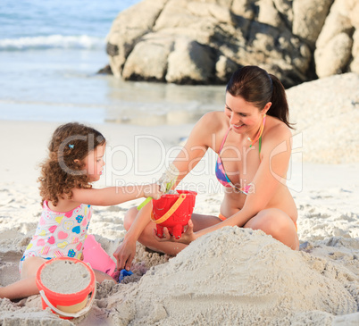 Daughter with her mother making a sand castle