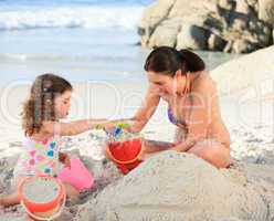Daughter with her mother making a sand castle