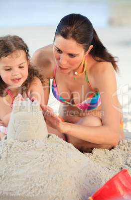 Daughter with her mother making a sand castle