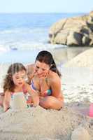 Daughter with her mother making a sand castle