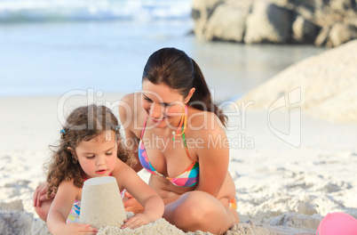 Daughter with her mother making a sand castle