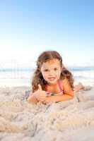 Little girl lying down on the beach