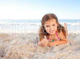 Little girl lying down on the beach