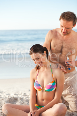 Man applying sun cream on his girlfriend's back