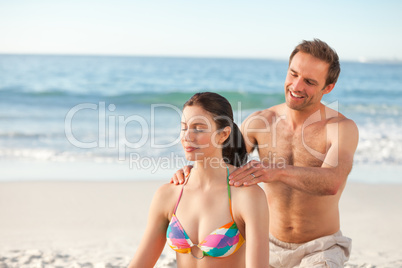 Happy man applying sun cream on his girlfriend's back