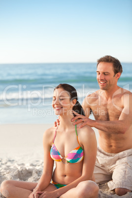 Happy man applying sun cream on his girlfriend's back