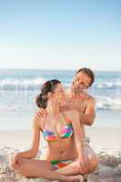 Attentive man applying sun cream on his girlfriend's back