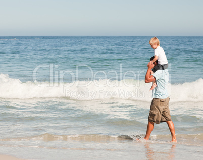 Father giving son a piggyback on the beach