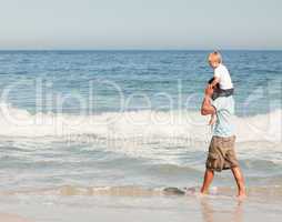 Father giving son a piggyback on the beach