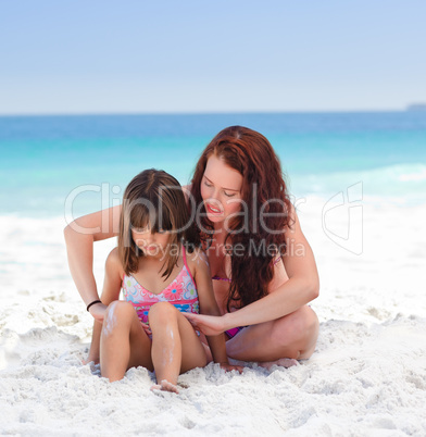 Mother applying sun cream on her daughter's back