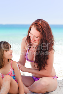 Mother applying sun cream on her daughter's back