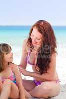 Mother applying sun cream on her daughter's back