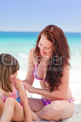 Mother applying sun cream on her daughter's back