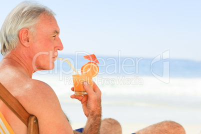 Retired man drinking a cocktail at the beach