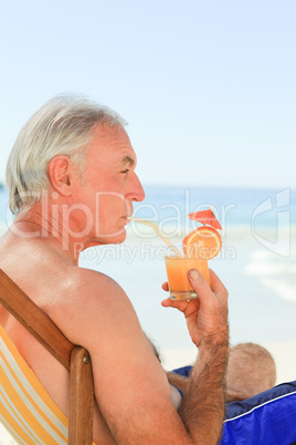 Retired man drinking a cocktail at the beach