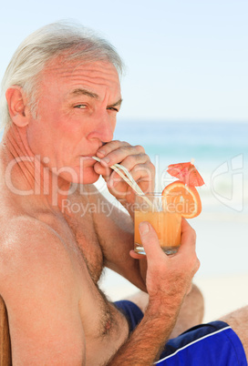 Retired man drinking a cocktail at the beach