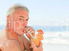Retired man drinking a cocktail at the beach