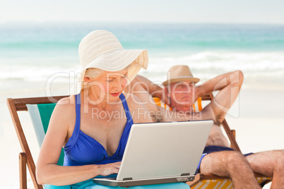 Woman working on her laptop while her husband is sleeping at the