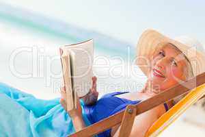 Elderly woman reading a book at the beach